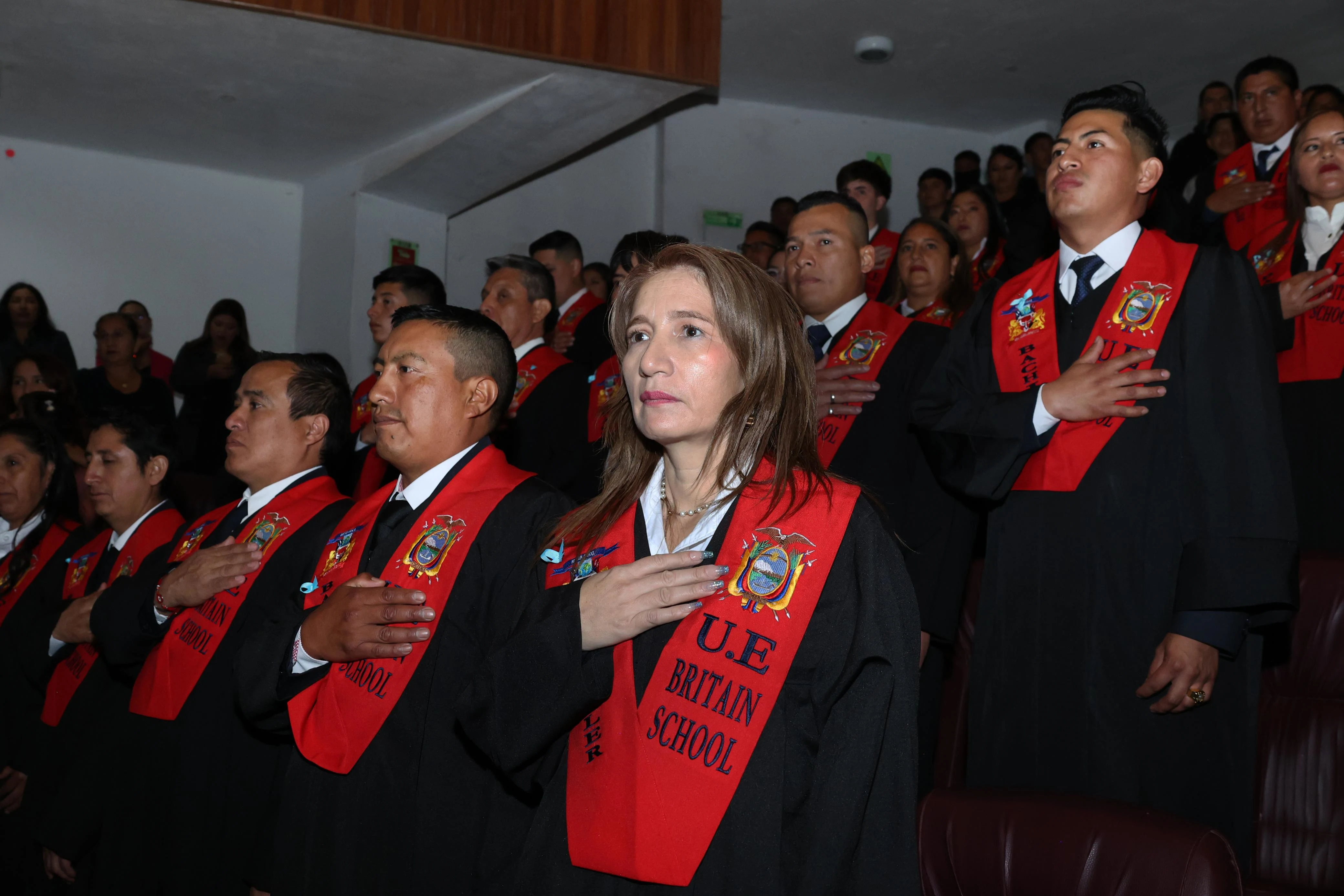 Estudiantes del Britain School en grado participando en acto cívico en el teatro